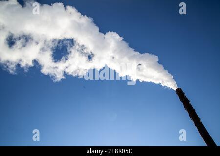 Una lunga nuvola di fumo bianco che fuoriesce da un camino metallico contro un cielo blu profondo. Foto Bo Arrhed Foto Stock