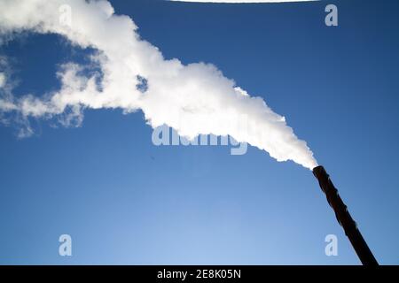 Una lunga nuvola di fumo bianco che fuoriesce da un camino metallico contro un cielo blu profondo. Foto Bo Arrhed Foto Stock