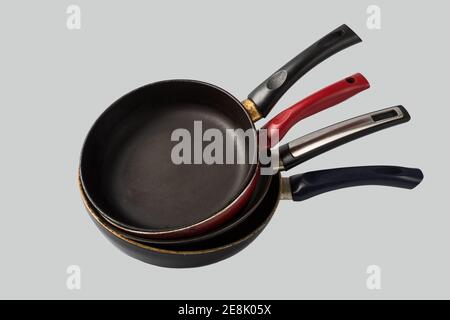 Pila di vecchi padelle usate graffiate su sfondo grigio chiaro Foto Stock