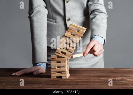 Uomo d'affari che rimuove il blocco di legno dalla torre Foto Stock