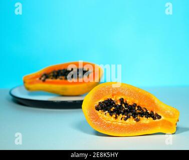 Due metà di Papaya con semi su sfondo blu, Minimalism trendy Food, sano e Detox mangiare, Raw lunch, CopySpace, frutta esotica Foto Stock