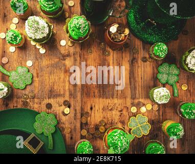 Happy St Patricks Day cupcakes con cappello leprechaun e pentola di monete su sfondo di legno, spazio copia Foto Stock