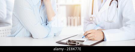 Donna-medico sconosciuto e paziente seduto al tavolo. Ottime notizie e servizio medico di alto livello Foto Stock