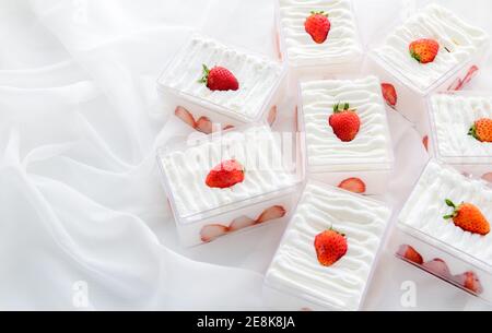 Shortcake di fragole in scatola di plastica su con fondo di stoffa e spazio di copia, il concetto minimo di torta e panificio Foto Stock