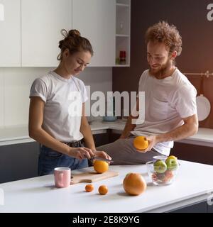 Coppia che si diverte a cucinare insieme in una cucina moderna in una nuova casa. Bella giovane coppia felice della loro nuova casa. Bella ragazza si nutre o la allatta Foto Stock