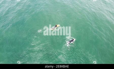 Due surfisti navigano su tavole da surf in un oceano tranquillo, vista dall'alto Foto Stock