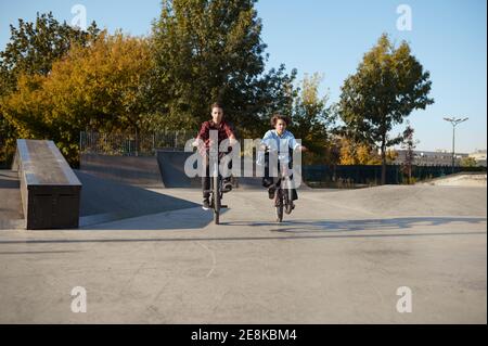 Giovani biker bmx che fanno trucchi in skatepark Foto Stock