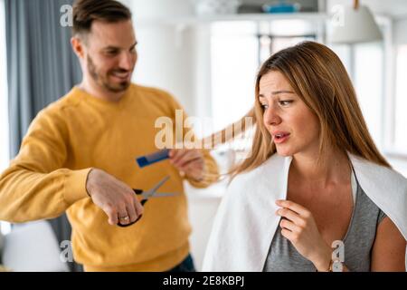 L'uomo fa un taglio di capelli alla donna a casa durante la quarantena. Foto Stock