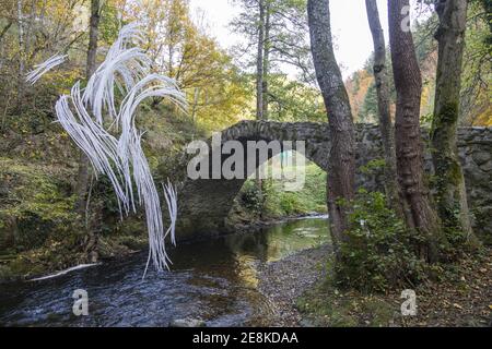 Auvergne, Francia. 24 Ott 2020. Vecchio ponte di pietra sul Couze Pavin con un'effimera opera d'arte di Anne Poinvilliers nella gola di Courgoul. Foto Stock