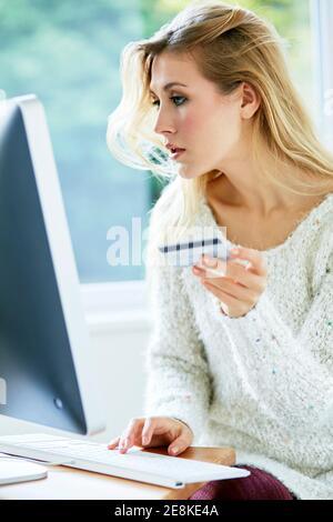 Donna che tiene la sua carta di credito che acquista articoli online Foto Stock