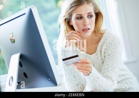 Donna che tiene la sua carta di credito che acquista articoli online Foto Stock