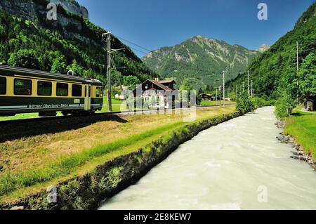 Un treno Berner-Oberland-Bahn lungo il fiume Weisse Lutschine nella valle di Lauterbrunnen. Foto Stock