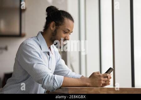 Positivo giovane maschio nero che ha piacere giocare gioco per cella Foto Stock