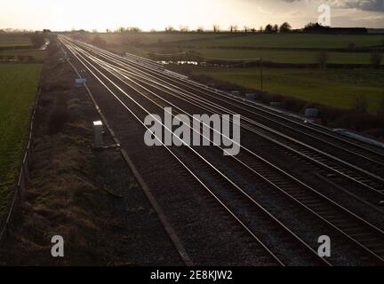 Vista serale delle piste ferroviarie della costa orientale Linea principale nello Yorkshire con luce solare dorata che si riflette rotaie Foto Stock