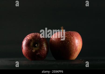 mele rosse su sfondo nero e gocce d'acqua su esso Foto Stock