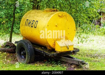 Vecchio rimorchio a forma di botte per il trasporto e la vendita di colore giallo brillante dell'epoca dell'Unione Sovietica, nel villaggio di Pskov. L'iscrizione Foto Stock