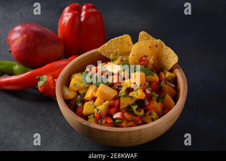 Salsa con mango, erbe, cipolle e peperoni, patatine di mais da vicino in una ciotola. Cibo messicano. Foto Stock