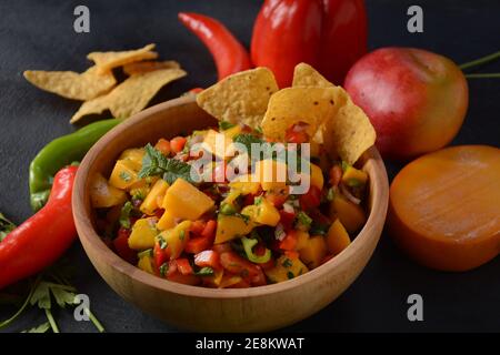 Salsa con mango, erbe, cipolle e peperoni, patatine di mais da vicino in una ciotola. Cibo messicano. Foto Stock