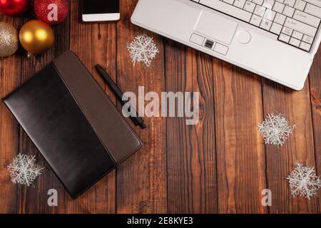 Sfondo natalizio per uomini d'affari, notebook in pelle con penna nera, portatile, telefono e decorazioni natalizie. Foto Stock