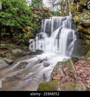 Chorlton Brook che cade sulle rocce della cascata dopo la pioggia pesante a Abney Hall Park, Cheadle, Stockport, Greater Manchester Foto Stock