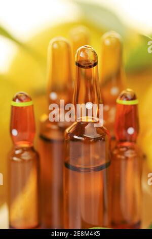 Iniezione di vitamina C. soluzione di vitamina C in ampolle di vetro marrone, limoni su fondo bianco. Ampolle e siero con vitamina C. organica Foto Stock