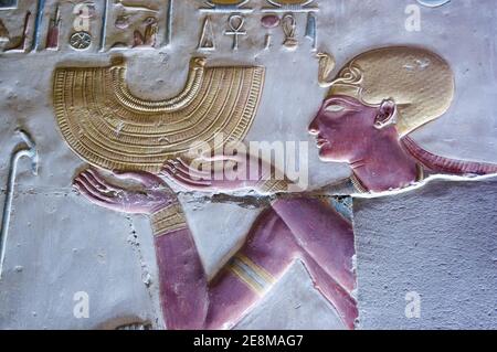 Antica scultura in bassorilievo egiziano che mostra il faraone Seti i tenendo una collana in stile colletto d'oro. Tempio di Abydos, El Balyana, Egitto. Scultura antica Foto Stock