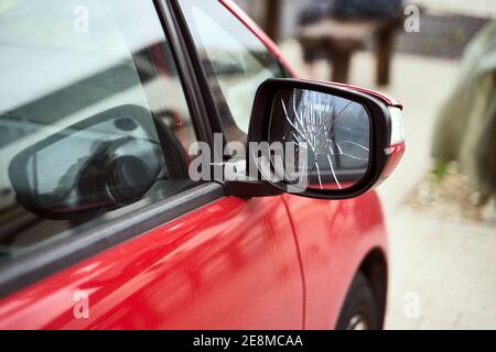 Auto rossa con specchietto retrovisore esterno laterale rotto parcheggiato sul via Foto Stock