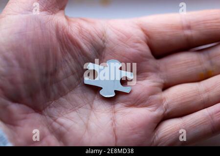 Concetto - primo piano di una persona che tiene l'ultimo pezzo del puzzle nel palmo della loro mano Foto Stock