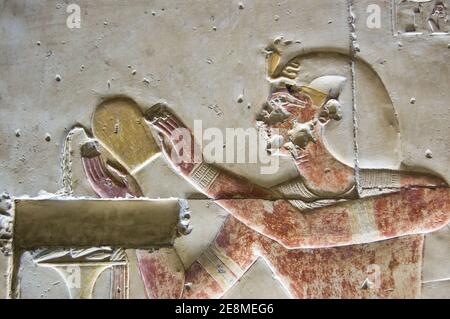 Antico bassorilievo egiziano che mostra il faraone Seti i versando liquido, probabilmente vino, come un'offerta al dio Osiride. Tempio di Abydos, Egitto. Antico c Foto Stock