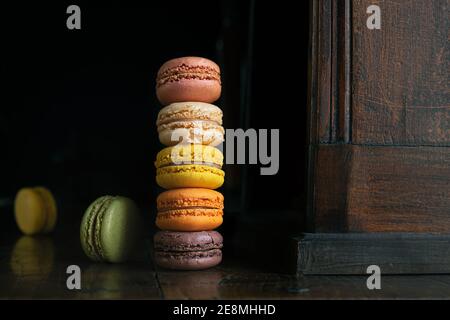Deliziosi macaron o macaron francesi classici e colorati su un vecchio bordo scuro vintage Foto Stock
