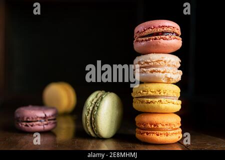 Una pila di deliziosi macaron o macaron francesi classici multicolore uno sfondo scuro Foto Stock