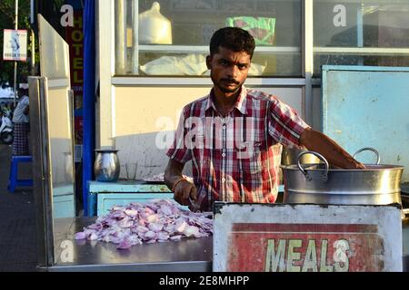 Kanyakumari, Tamil Nadu, India - Febbraio, 2017: Uomo indiano che taglia la cipolla per cucinare il cibo di strada in un piccolo caffè sulla strada Foto Stock