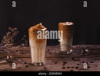 Caffè Dalgona. Bevanda ghiacciata montata con caffè istantaneo popolare in Corea cocktail cremoso in bicchieri alti. Fotografia di cibo con moody scuro Foto Stock