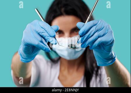 Closeup di utensili dentali in metallo nelle mani del dentista donna su sfondo blu Foto Stock