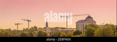 Vista panoramica sul centro di Magdeburgo con molte gru all'orizzonte durante il tramonto rosso, in Germania Foto Stock