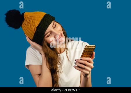 Donna che effettua la videochiamata utilizzando un telefono isolato su sfondo blu. Felice donna sorridente che parla con gli amici in videochat. Bellezza, emozioni della gente e t Foto Stock