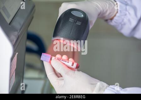 Il tecnico esegue la scansione dei codici a barre sulla provetta per campioni biologici in laboratorio della banca del sangue Foto Stock