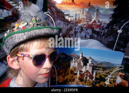 Germania/Baviera/Re Ludwigs Castel Schloss Neuschwanenstein giovane turista con cappello bavarese di fronte alle cartoline kitsch. Foto Stock