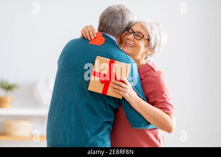 Coppia anziana nella giornata di San Valentino. Gioiosa bella donna anziana sorridente mentre riceve un regalo dal marito. Foto Stock