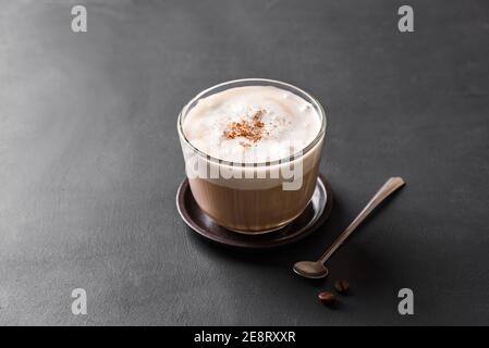 Cappuccino. Caffè fresco con deliziosa schiuma di latte e cannella su tavolo scuro, spazio copia. Foto Stock