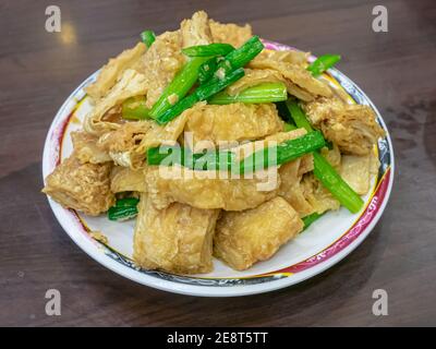 Un primo piano della tradizionale pelle tofu taiwanese fritta (foglio di cagliata di fagioli), cibo taiwanese su tavolo di legno al ristorante nel mercato notturno di Taiwan. Foto Stock