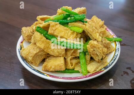 Un primo piano della tradizionale pelle tofu taiwanese fritta (foglio di cagliata di fagioli), cibo taiwanese su tavolo di legno al ristorante nel mercato notturno di Taiwan. Foto Stock