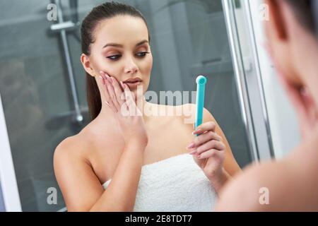 Donna che guarda sulla riflessione nello specchio dopo la doccia Foto Stock