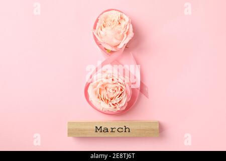 8 in nastro, blocco di legno con testo marzo e rose su sfondo rosa Foto Stock