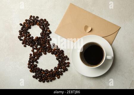 Otto di chicchi di caffè, una tazza di caffè e una busta su sfondo bianco Foto Stock