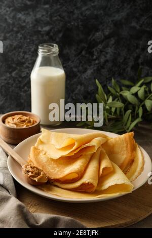 Concetto di deliziosa colazione con piatto di crepes con arachidi burro su tavola di legno Foto Stock