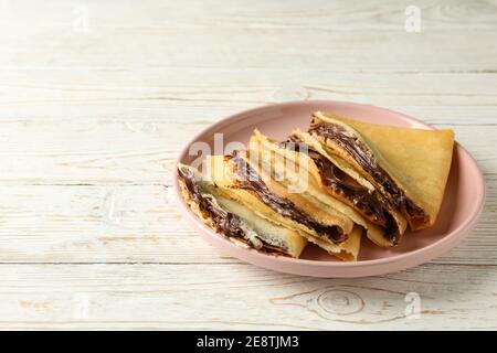 Piatto di crepes con pasta di cioccolato su sfondo bianco di legno Foto Stock