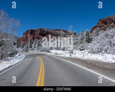 Colorado Highway 90 a Paradox Valley con alberi sempreverdi coperti di neve e gelo contro le soleggiate rocce rosse in prima Winder, fine autunno Foto Stock