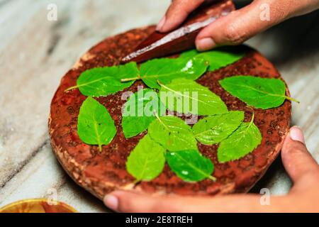 Hindu Puja preparazione rituale background. Immagine closeup di bastone di legno di sandalo o chandan con macinazione di pietra e basilico santo o foglie di tulsi. Rituale per Foto Stock