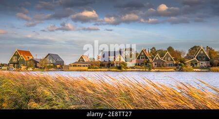 Tradizionale scenario di villaggio con case in legno sul lungomare a Groot Schermer, Olanda del Nord, Paesi Bassi Foto Stock